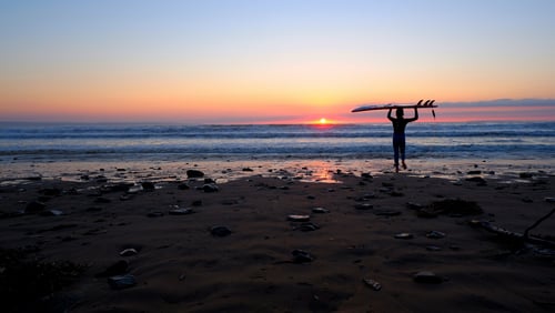 boy takes surfboard to sea on saunton sands