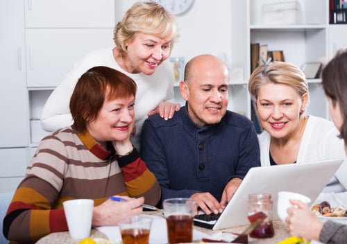 friends gather round laptop to organise a staycation