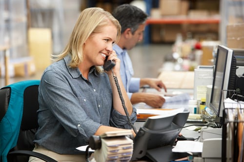 Business woman answers phone at desk