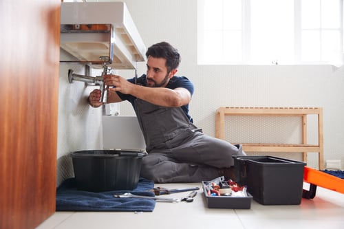 male plumber fixes leak in bathroom