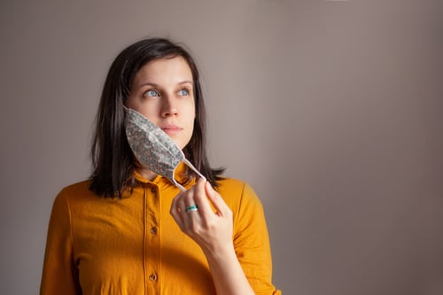 young woman takes off her protective mask