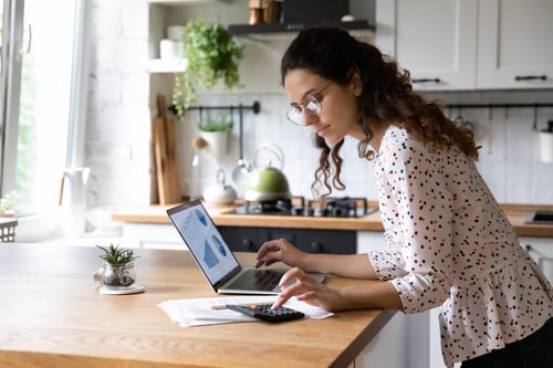 woman calculates finances at kitchen table