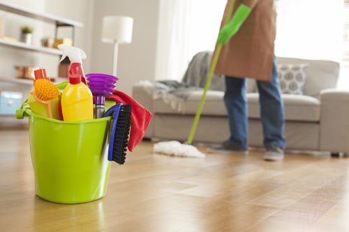 man mopping floor with cleaning supplies in focus